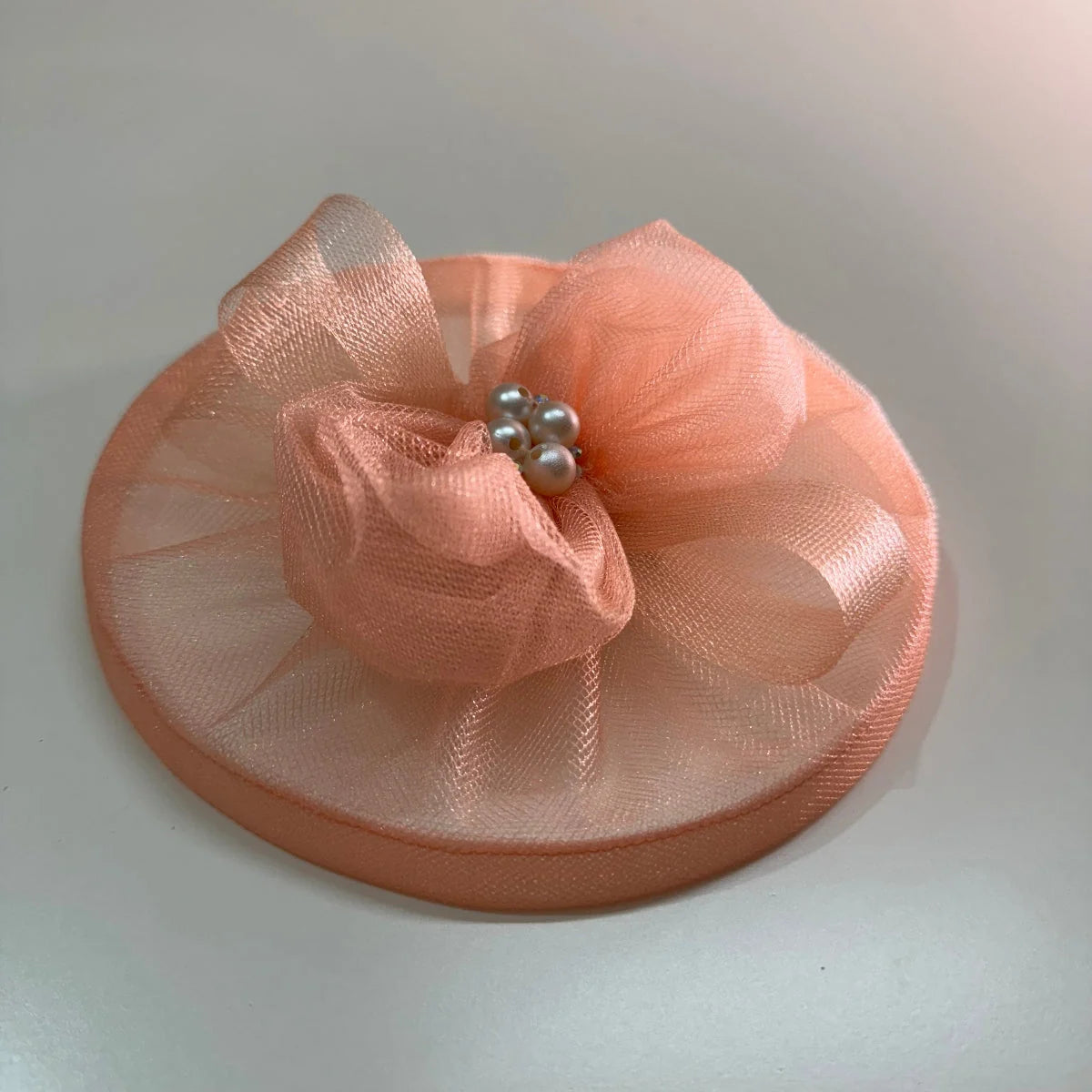 Elaria Vintage Peach Fascinator with sculpted peach mesh loops, a satin-bound round base and pearl cluster centre.