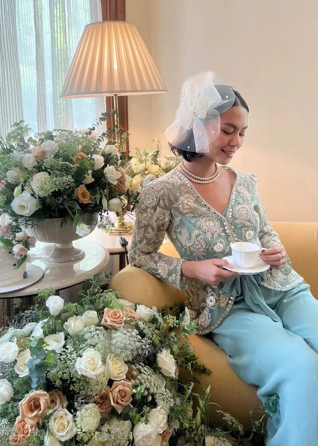 Woman wearing a sculptural white fascinator with a pastel outfit